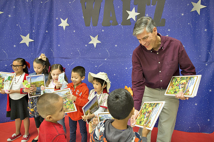 El autor del libro infantil James Luna entregando su libro a los estudiantes de la Escuela Primaria Carl Waitz, en Alton, Texas.